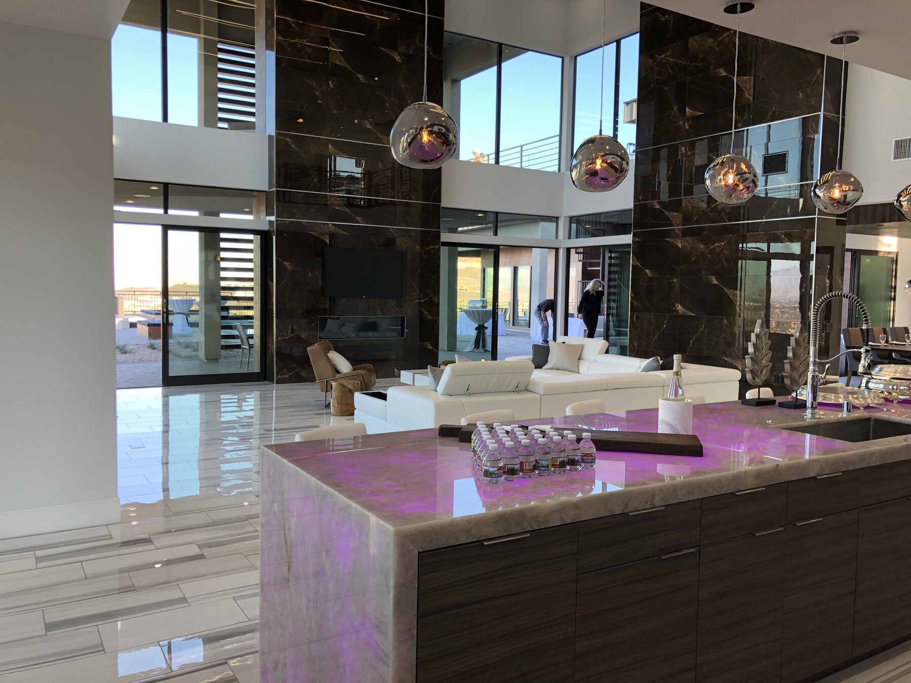 The same countertop under DMX control glowing magenta, seen across the double height great room