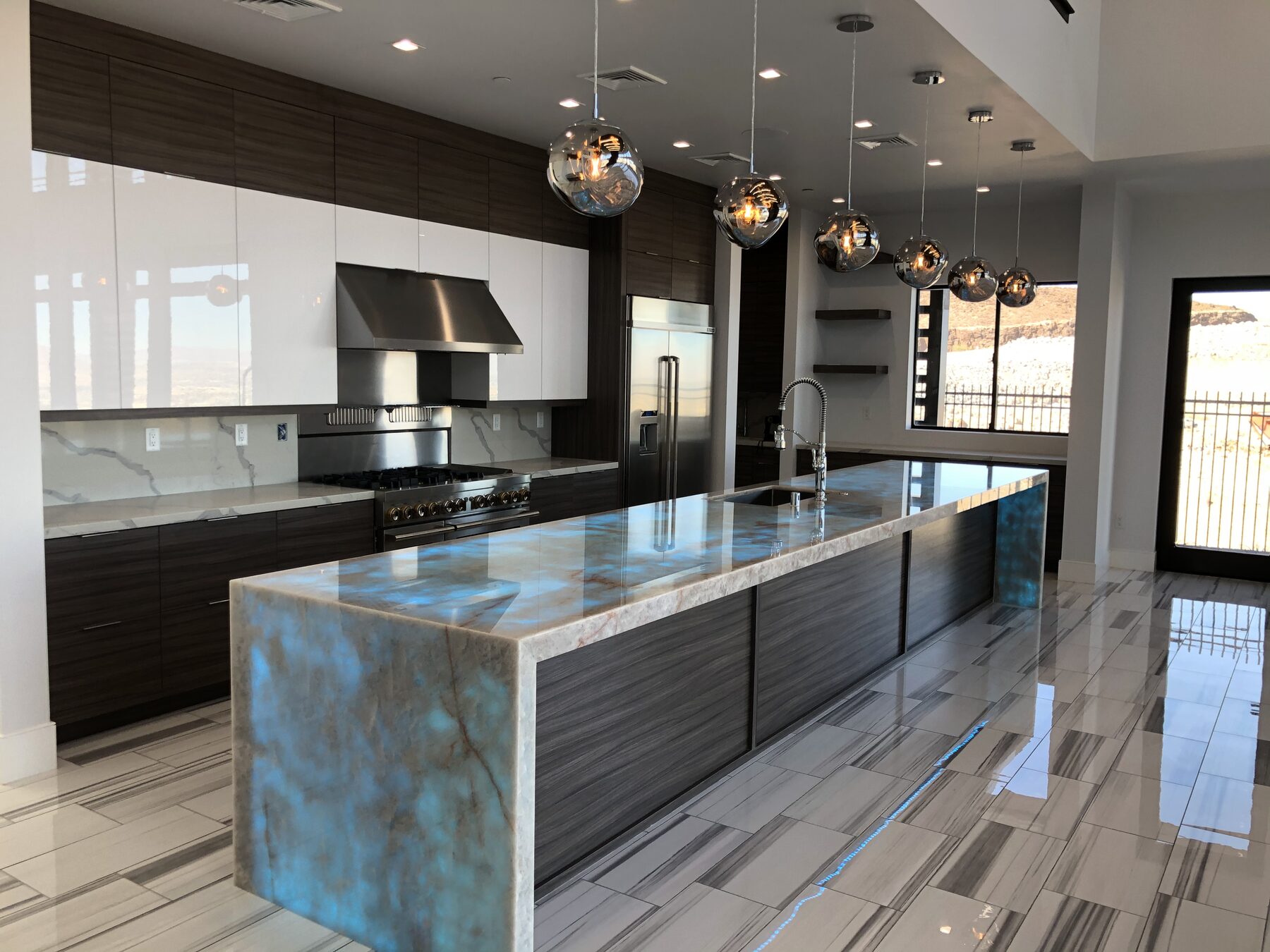 Kitchen island topped with backlit onyx glowing teal, lit from within along its full length