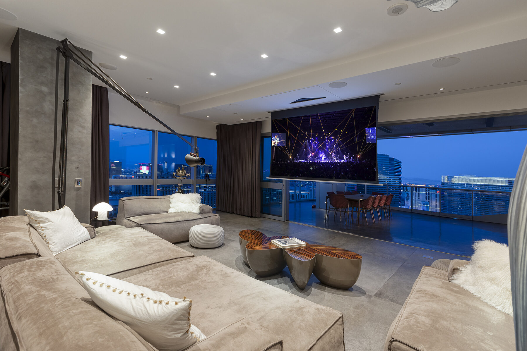 The 106 inch motorized screen lowered in front of the pocket doors, playing content while the city lights remain visible alongside it