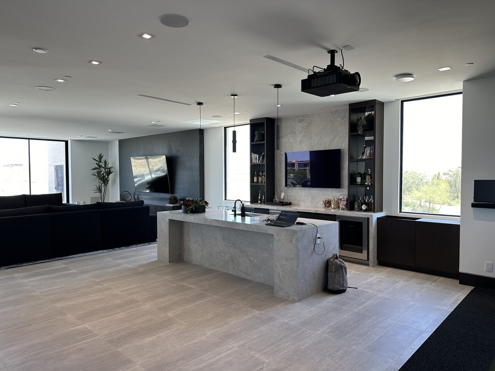 Great room with a ceiling mounted projector, wall display and a stone island