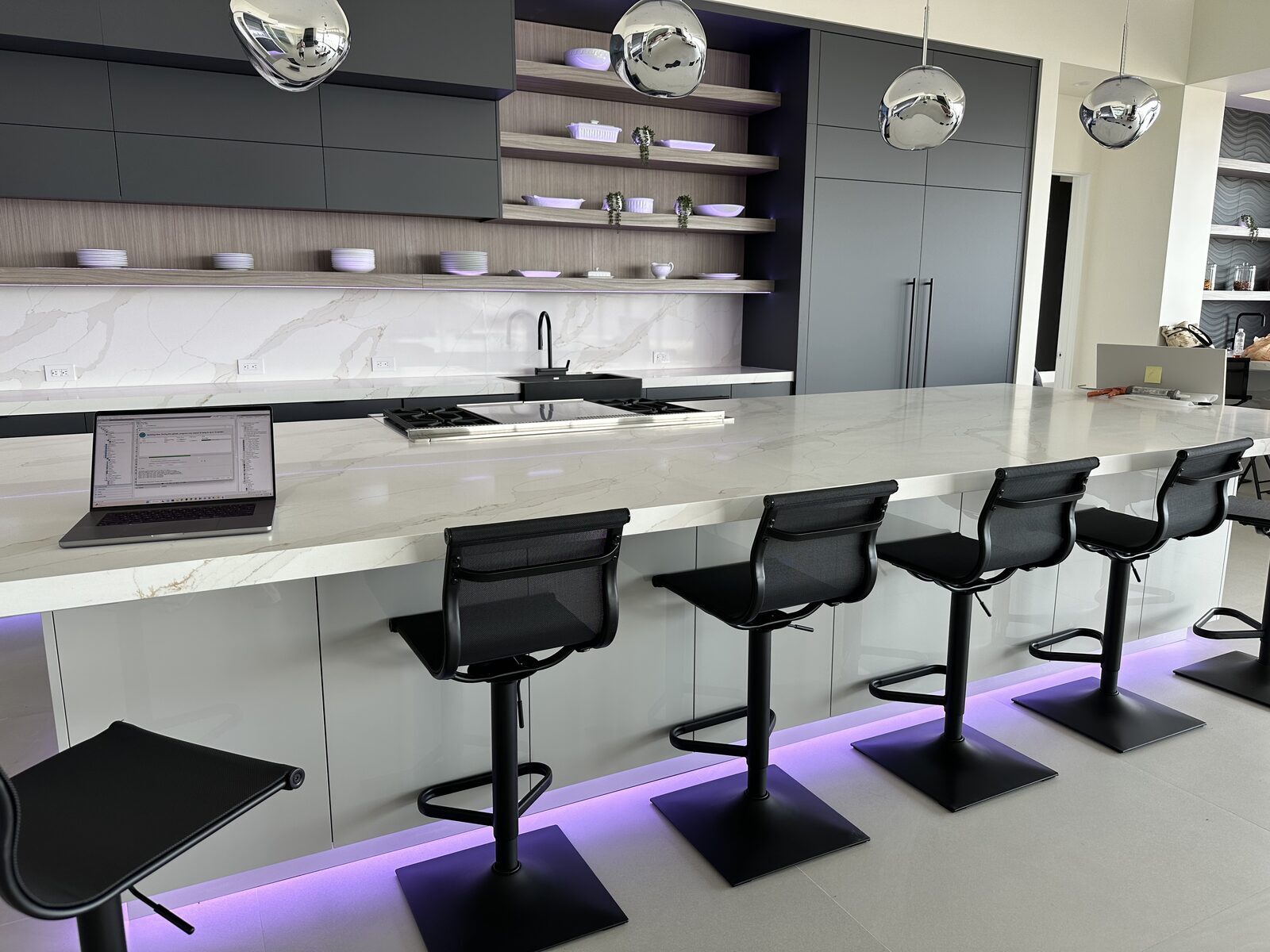 Island seating with concealed lighting washing the floor beneath the counter and polished pendants above