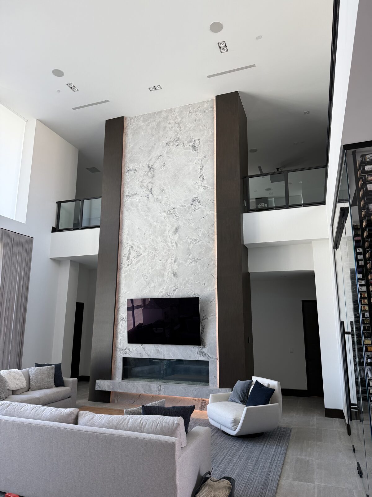 Double height living room with a full height stone fireplace and a display set into the surround