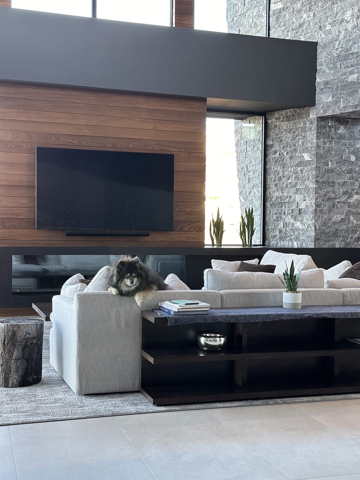 Living room with a display set into a timber wall beside a full height stone chimney