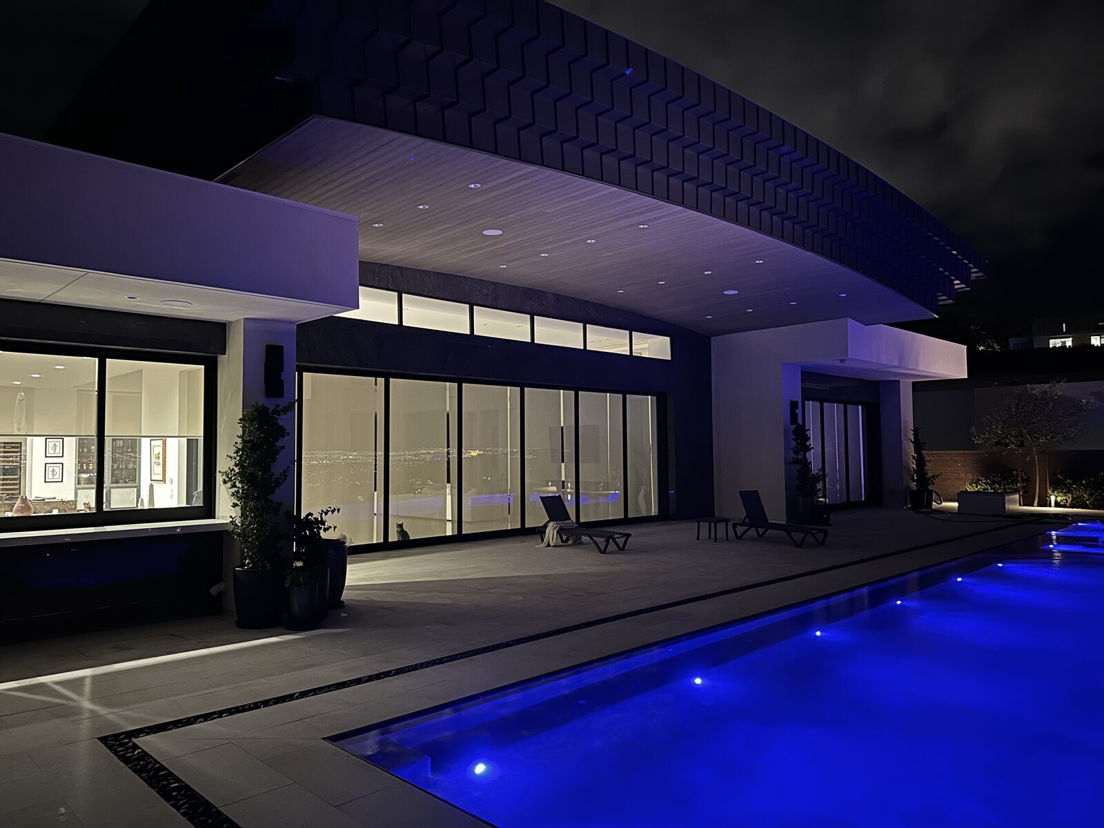 Pool terrace at night with the water lit from within and the covered patio lit above
