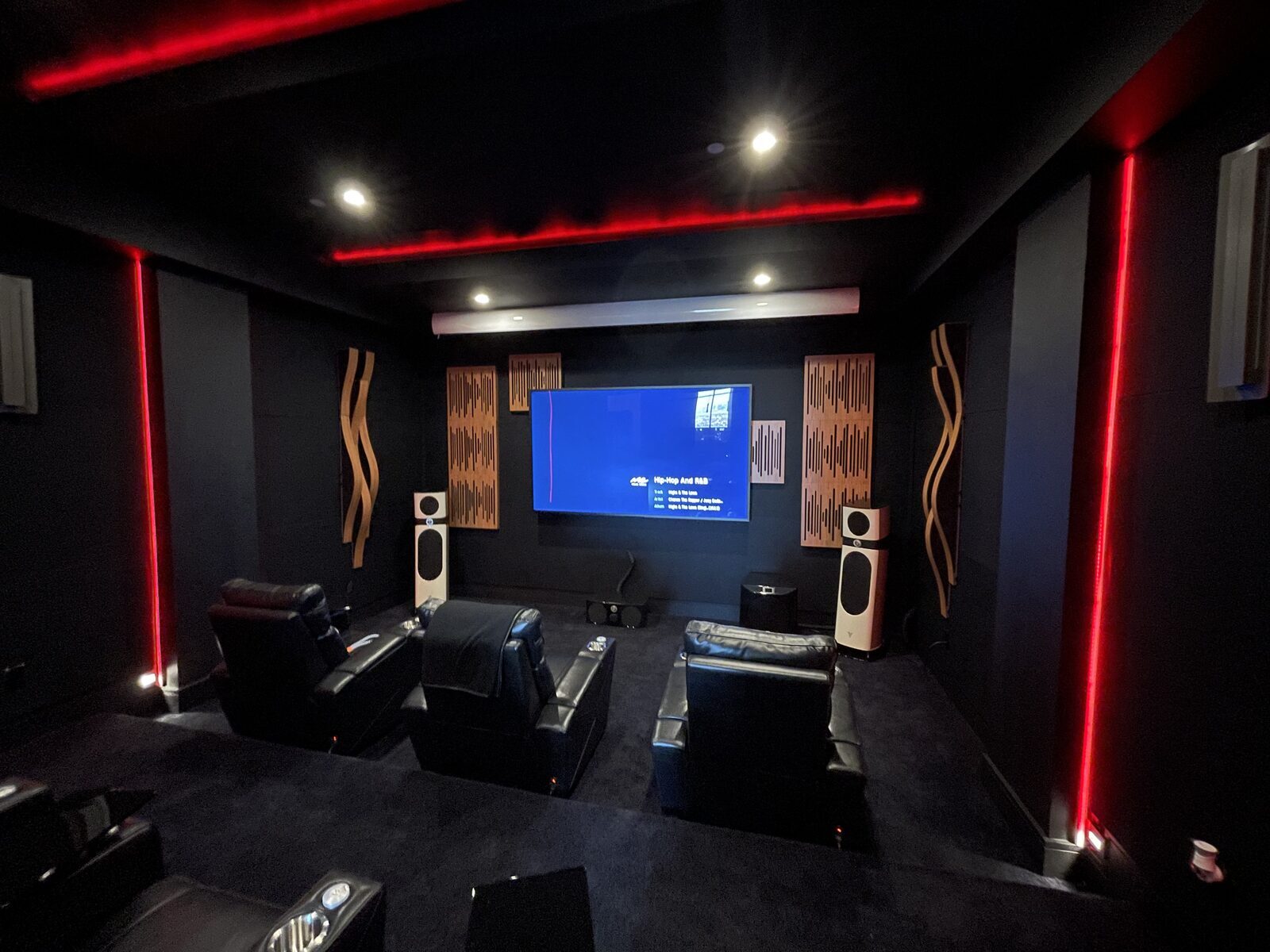Private theater with red perimeter accent lighting, wood acoustic panels and tiered seating
