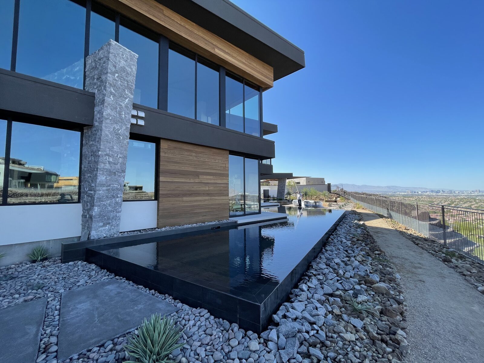 Reflecting pool running alongside a stone and timber elevation with the valley beyond